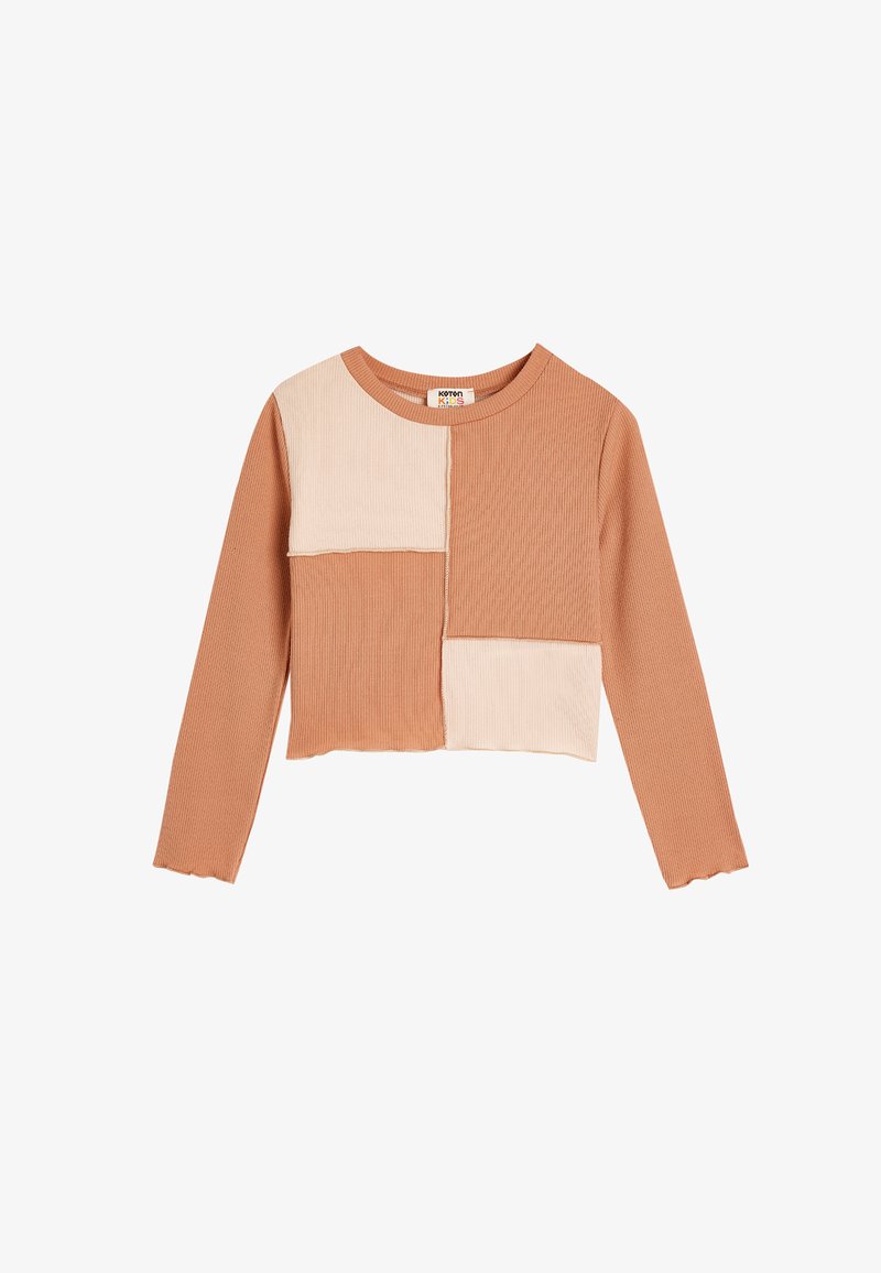 Ribbed, cropped long-sleeve top featuring a patchwork design in warm beige and light cream colors with scalloped hem detailing.
