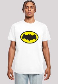 White cotton t-shirt featuring a large black and yellow Batman logo in an oval shape, crew neck, and short sleeves.