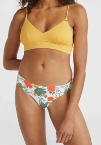 Rumena braleta z V-izrezom in tankimi naramnicami, v kombinaciji z belimi bikinami z cvetličnim motivom, ki prikazujejo oranžne in zelene rože.