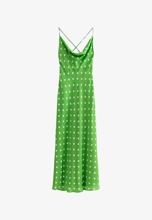 Abito lungo verde senza maniche con pois bianchi, caratterizzato da sottili bretelle incrociate sulle spalle e scollo drappeggiato.