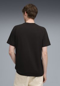 Sort t-shirt med korte ærmer, rund halsudskæring og raglanærmer. Glat tekstur, enkelt design, der viser en del af ryggen.