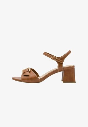 Brun lædersandal med blokhæl, ankelsnor og spænde. Har åben tå og detaljeret syning langs kanterne.