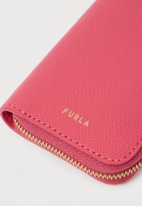 Rozā teksturēta ādas maks ar zelta rāvējslēdzēja aizdari un izspiestu "Furla" logotipu. Ir noapaļotas malas un gluds iekšējais oderējums.