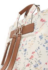 Kwiatowy plecak w kolorze białym, z wielokolorowymi nadrukami kwiatów, brązowymi akcentami ze skóry syntetycznej oraz srebrnymi elementami z zamkami błyskawicznymi.