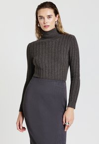Maglione a collo alto grigio scuro a coste con maniche lunghe, abbinato a una gonna a tubino grigia, caratterizzata da una texture liscia e un design aderente.