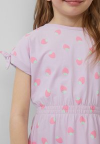 Robe lavande à manches courtes, dotée d'une taille réglable par cordon. Décorée d'un motif de petites fraises roses et de feuilles vertes.
