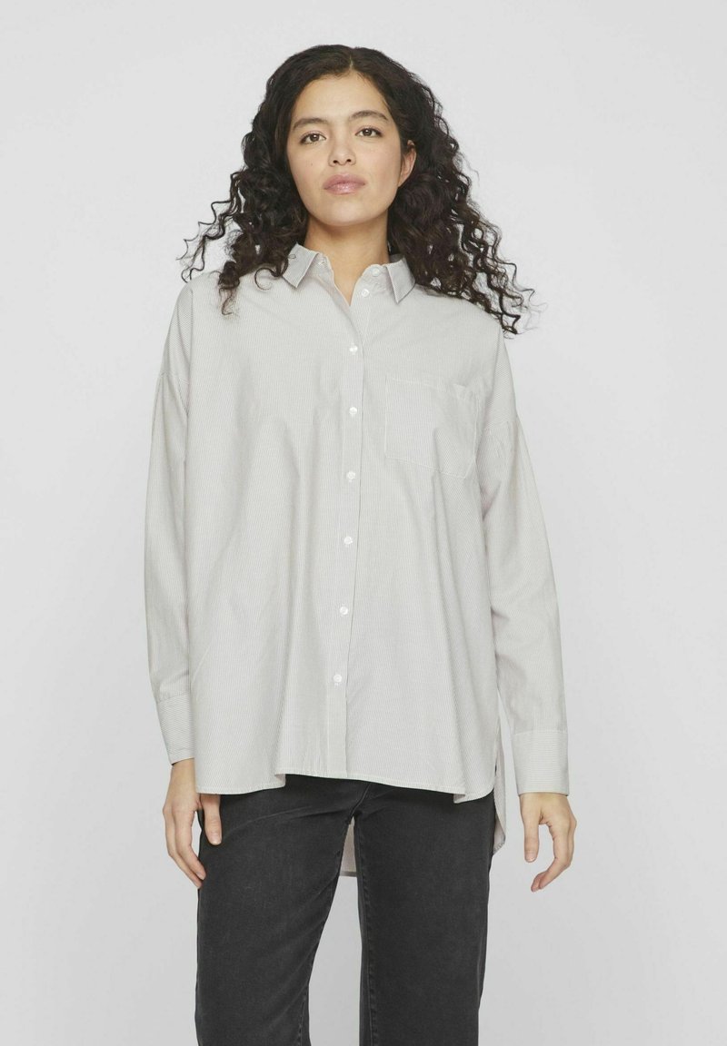 Camisa abotonada en gris claro con un patrón de rayas finas, cuenta con un bolsillo en el pecho, mangas largas y un corte holgado.