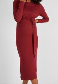 Kohokuvioitu, maroon midi-mekko, jossa on pitkät hihat ja sidottava vyötäröyksityiskohta. Mekko on slim fit -tyylinen ja sillä on suora siluetti.