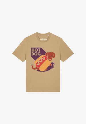 T-shirt beige avec un graphisme d'un teckel brun dans un pain hot dog, avec du ketchup et le texte "HOT DOG" en lettres capitales violettes.