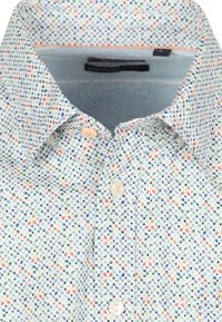 Lichtblauw shirt met een klein, verspreid meerkleurig stippenpatroon. Voorzien van een klassieke kraag en twee knoopsluitingen bij de hals.