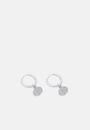 Pendientes de aro de plata con un colgante circular texturizado. Los colgantes presentan un diseño intrincado en relieve.