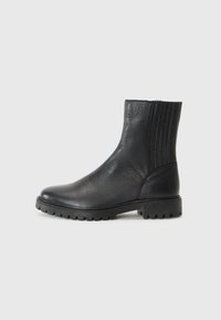 Botas de tobillo de cuero negro con un acabado texturizado, paneles laterales elásticos y una suela de goma robusta con pequeños tacos para mayor tracción.