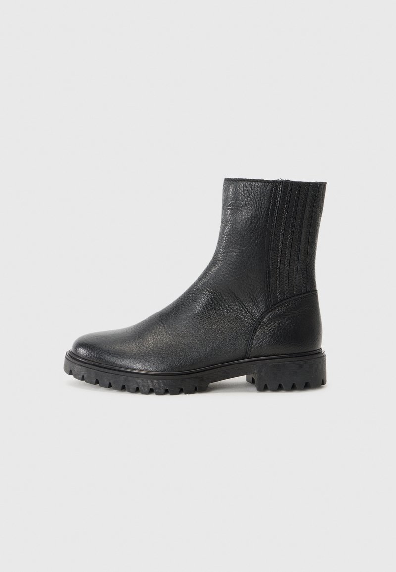 Botas de tobillo de cuero negro con un acabado texturizado, paneles laterales elásticos y una suela de goma robusta con pequeños tacos para mayor tracción.
