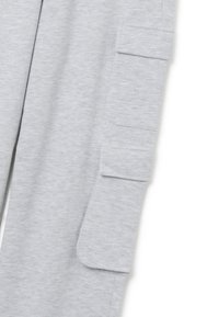 Hellgraue Sweatpants aus einem weichen Baumwoll-Mix, mit Cargo-Taschen und entspannter Passform. Minimale Nähte und glatte Textur.