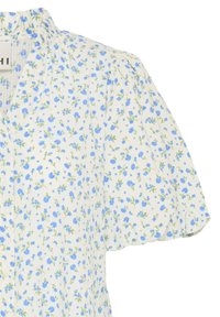 Blouse blanche avec manches courtes ballons, imprimé floral bleu, devant boutonné et détails subtils froncés aux épaules.