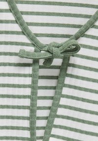 Groen en wit gestreepte stof met een textuurafwerking. Heeft een gestrikte strik bij de halslijn, omlijst door een effen groene rand.