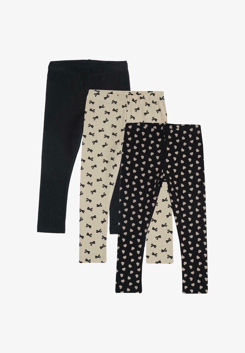 Trois paires de leggings : une noire unie, une crème avec un motif de nœuds noirs et une noire avec des cœurs rose clair. Tous sont en tissu extensible.