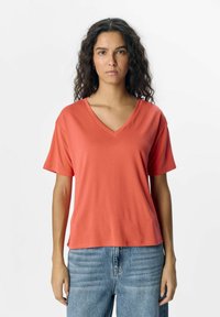 Korallfarvet V-hals t-shirt lavet af blødt stof med korte ærmer, med en afslappet pasform og en glat overflade. Sammen med lyseblå jeans.