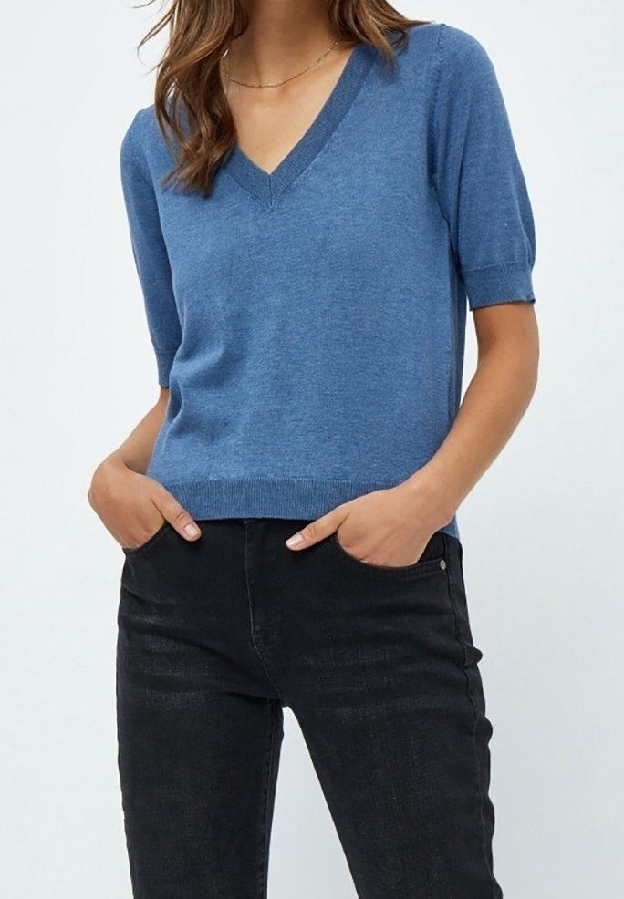 Pull bleu à manches courtes avec col en V et bordure côtelée, associé à un jean noir. Le tissu semble doux et léger.