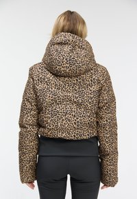 Padded jacket z dużym kapturem, w brązowej podstawie z czarnym nadrukiem w panterkę. Projekt obejmuje dopasowaną talię i elastyczne mankiety.
