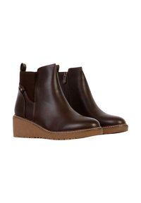 Bottes cheville en cuir marron avec semelle compensée, dotées d'une fermeture éclair latérale, d'une texture lisse et d'un petit bouton décoratif sur le côté.