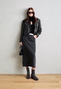Black leather biker jacket, fitted black turtleneck with keyhole, black denim skirt, black ankle boots, and a black handbag. Smooth textures.