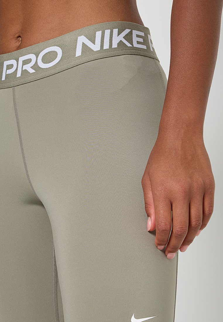 Leggings Nike Pro en verde oliva, con una amplia cinturilla de logo blanco, textura suave y silueta ajustada con un mínimo detalle de costura.