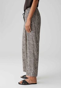 Pantalons amples à taille haute avec un motif abstrait noir et blanc. Dotés d'une taille élastique avec un cordon de serrage, en tissu léger.