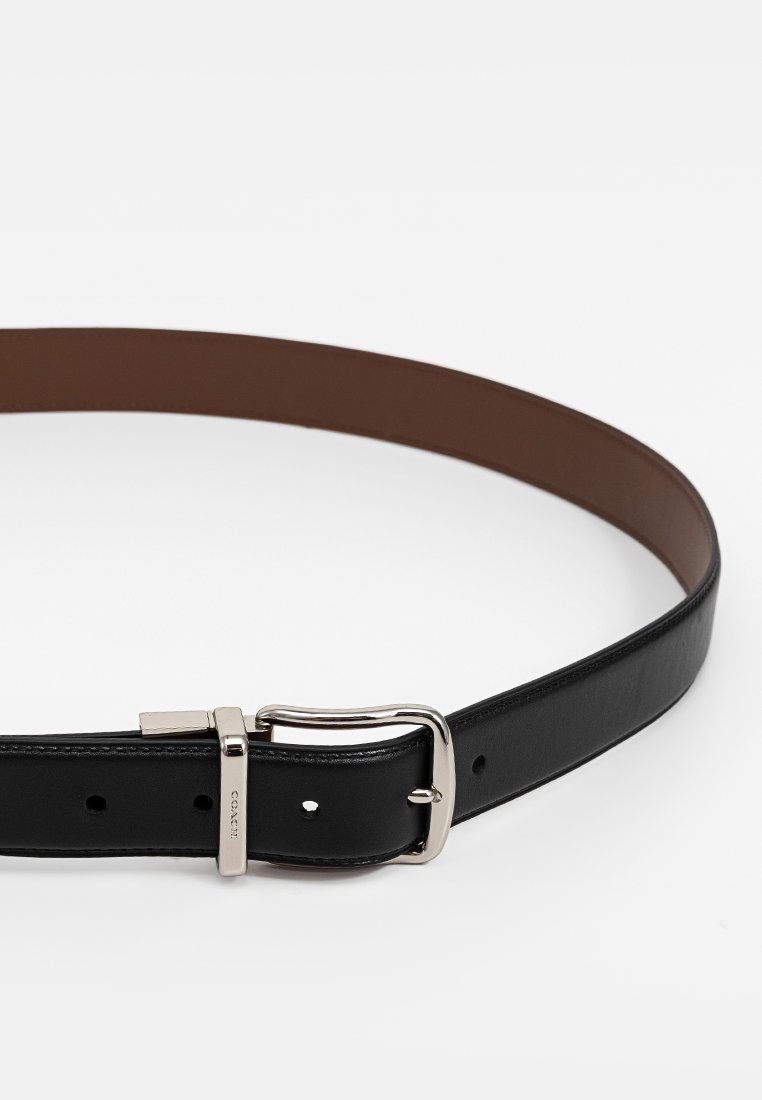 Ceinture en cuir noir avec boucle rectangulaire en argent et côté intérieur marron, posée à plat sur un fond blanc.