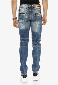 Vervaagde blauwe denim jeans met een skinny fit, voorzien van meerdere zakken, gestikte accenten en een logo patch op de tailleband.