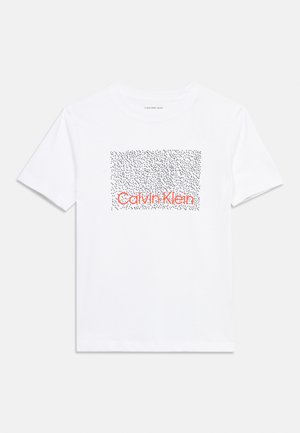 Hvid T-shirt med korte ærmer, med en sort prikket rektangel og orange "Calvin Klein"-tekst centreret på brystet.