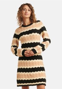 Strickkleid mit wellenförmigen Streifen in Schwarz, Creme und Pfirsichfarben. Lange Ärmel und ein runder Ausschnitt, aus strukturiertem Stoff.