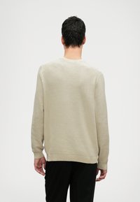 Helles beiges Sweatshirt mit strukturiertem Strickmuster, Rundhalsausschnitt und gerippten Bündchen und Saum. Figurbetonte Silhouette und lässiger Stil.