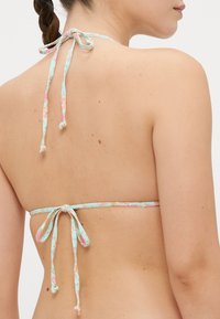 Cvjetni bikini top u svijetloplavoj boji, s podesivim vezicama oko vrata i na leđima. Glatka tkanina s uzorcima ružičastih i žutih cvjetova.