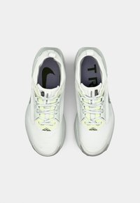 Baskets de sport blanches avec une tige en maille, de subtils accents jaunes et une semelle texturée. Présente un logo noir et un intérieur rembourré pour le confort.
