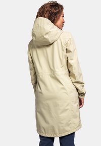 Helle beige wasserdichte Jacke mit Kapuze, verstellbaren Manschetten und tailliertem Schnitt. Glatte Textur, knielange Ausführung und ohne erkennbare Muster.