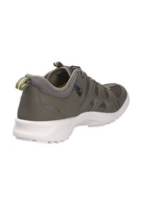 Chaussure de sport grise avec tige en maille et synthétique, semelle blanche, accents texturés et détails réfléchissants sur les lacets et le talon.