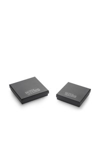 Dve kvadratne črne kartonske škatle s pokrovi, ena večja od druge; obe imata na vrhu embosirano besedilo "PRAVI UPORNIKI!"