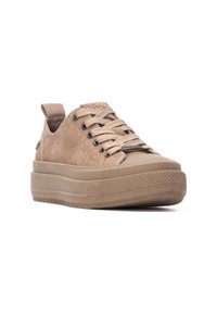 Zapatilla de lona color beige con suela gruesa, cordones frontal, ojales reforzados y tirador en el talón. Presenta una suela de goma texturizada.