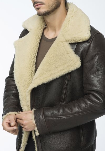 Giacca in pelle marrone con colletto in shearling color crema, dotata di chiusura con zip e due tasche frontali. Finitura in pelle texture.