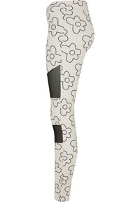Hvite leggings med svart blomstermønster; har svarte mesh-paneler på sidene; kroppsnær passform og elastisk stoff.