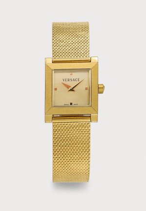 Χρυσόχρωμο τετράγωνο ρολόι χειρός Versace με μεταλλικό πλέγμα στο λουράκι, μινιμαλιστικό καντράν που δείχνει 10:10 και την ένδειξη "Swiss Made" στο καντράν.