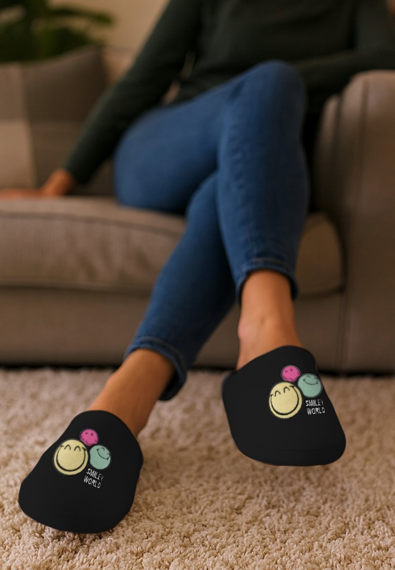 Pantofole nere senza lacci con faccine sorridenti ricamate colorate e il testo "SMILEY WORLD." Materiale morbido in tessuto con design a punta arrotondata.