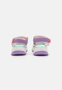 Fargerike sandaler med lilla, grå og rosa stropper. Har justerbare lukkinger og en strukturert hvit såle med lilla detaljer.