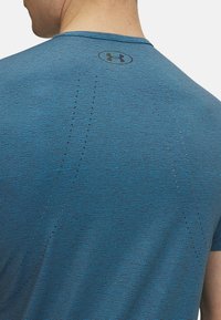 Sinine sportlik särk tekstuuriga mustriga, ümar kaelus ja Under Armouri logo seljal. Omab väikeseid ventilatsiooniauke õmbluste ääres.