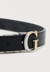 Μαύρη δερμάτινη ζώνη με μεταλλική αγκράφα σε σχήμα γράμματος G, με ασημί και χρυσαφί λεπτομέρειες. Εσωτερική πλευρά με υφή και μοτίβο λογότυπου. Ρυθμιζόμενο μέγεθος.