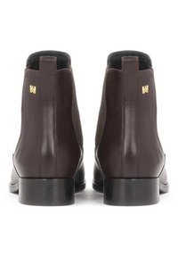 Bottes Chelsea en cuir brun foncé avec une finition lisse, panneaux latéraux en élasthanne et un petit talon noir. Petit logo doré à l'arrière.