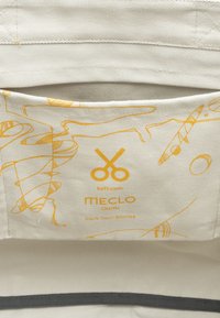 Canvas etui in licht beige met gele abstracte lijnpatronen. Bevat een logo met scharen en de tekst "Pack Your Stories." Textuur binnenzijde.