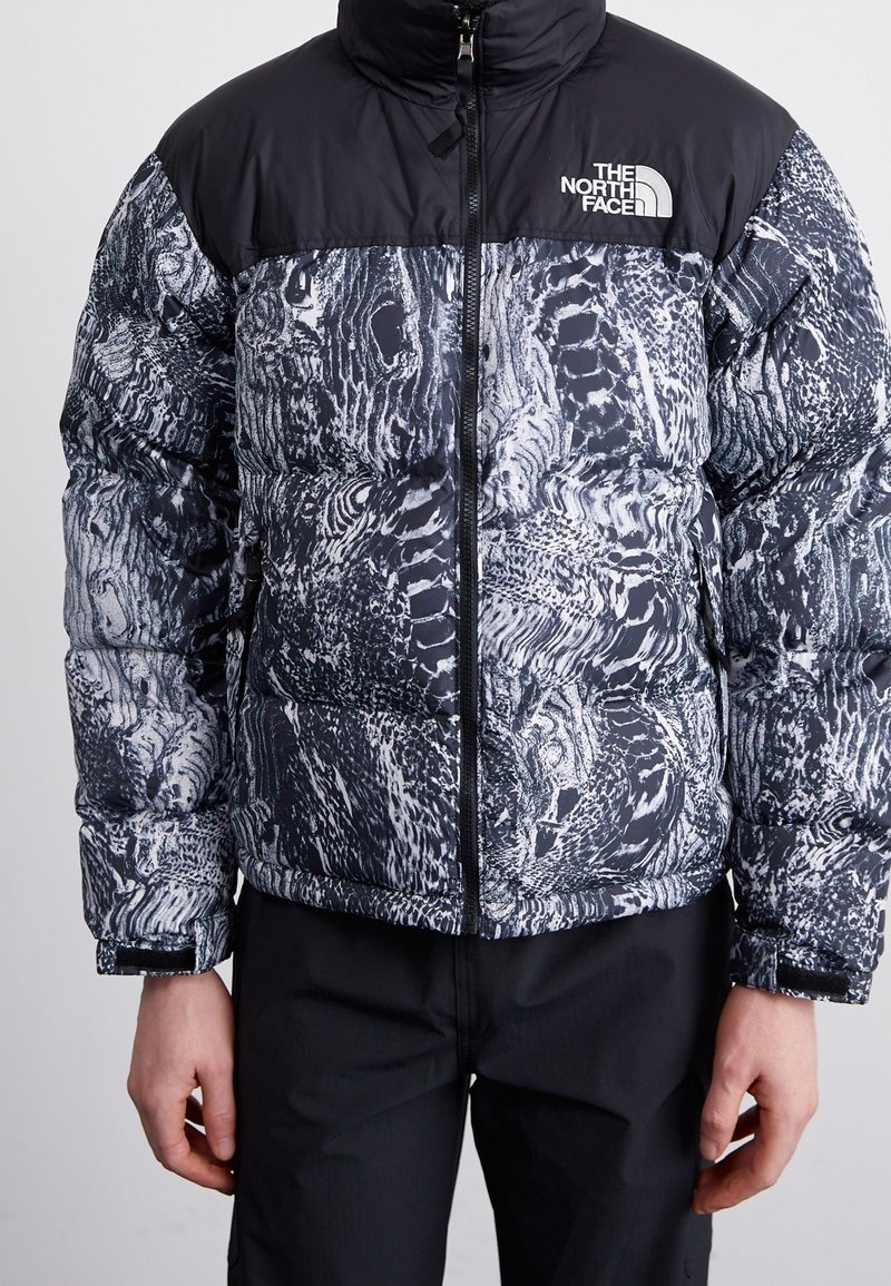 Dunjakke med en sort øverste sektion og en tekstureret grå og hvid mønstret nederste sektion. Lynlås og logo på brystet.