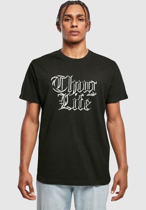 Černé bavlněné tričko s bílým grafickým designem, na kterém je nápis "Thug Life". Tričko má krátké rukávy a kulatý výstřih.